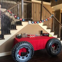 a red table topped with a giant tire next to a bannister and stairs