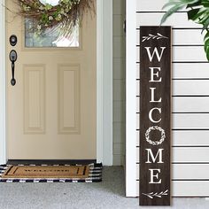 a welcome sign sitting on the front door of a house next to a potted plant