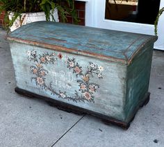 an old wooden box sitting on the side of a building with flowers painted on it