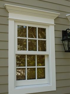 a white window sitting on the side of a gray house next to a light fixture