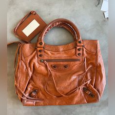 Authentic Balenciaga Large City Bag In Caramel Leather (2011). Zips Across Top For Full Closure. *If You Want To Use The Crossbody Strap, You’d Need To Get The Attachment Fixed, As It Has Broken Off. All Pieces Shown Are Included. Other Than This The Bag Is In Decent Condition With Some Wear To Leather As Can Be Seen In Photos. Comes With Dust Bag, Mirror And All Original Tags. Size: 13” L X 11” H X 4” W Bags Balenciaga, Bag Mirror, City Bag, Balenciaga Bag, Crossbody Strap, Size 13, Balenciaga, Caramel, The Bag