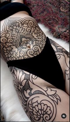 a woman with tattoos on her stomach laying down