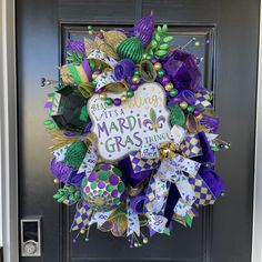 a wreath with mardi gras decorations hanging on the front door to welcome guests