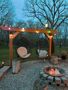 an outdoor fire pit with two hanging chairs