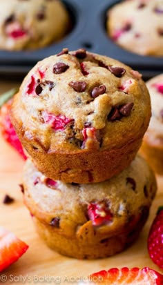 three strawberry chocolate chip muffins stacked on top of each other next to strawberries