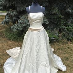 a wedding dress on display in front of some trees