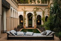 a couch sitting in the middle of a courtyard next to a pool with lots of greenery