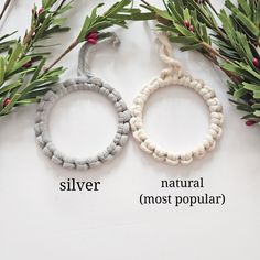 two bracelets with silver, natural and most popular beads next to evergreen branches on a white surface