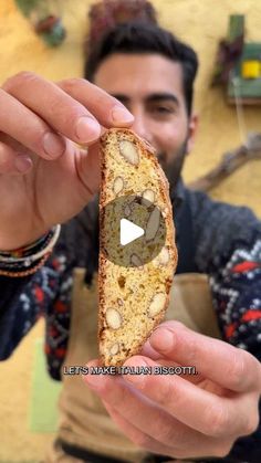 a man holding a piece of bread with nuts on it in front of his face