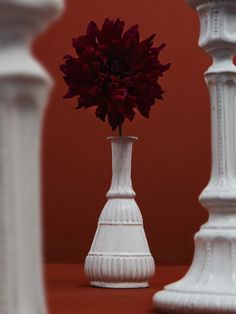 two white vases with red flowers in them on a table next to each other