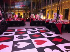 an indoor dance floor is decorated with black, red and white playing cards on it