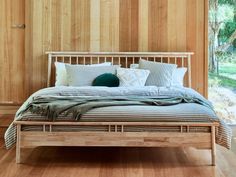 a bed that is made up with pillows and blankets on top of the headboard