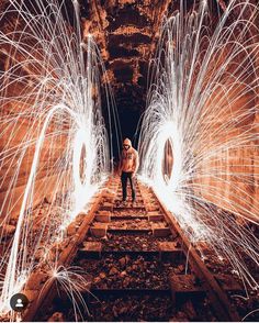 a man standing on train tracks surrounded by sparks