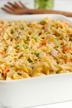 a casserole dish with noodles, peas and carrots