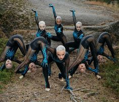 a group of women in black and blue bodysuits doing yoga poses on the ground