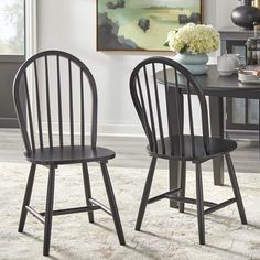 two black chairs sitting next to each other on top of a carpeted floor in front of a dining room table