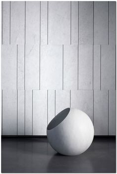 a large white ball sitting on top of a floor next to a wall with vertical lines