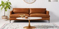 a living room with a brown leather couch and white coffee table