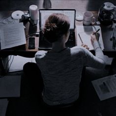 a person sitting at a desk with a laptop and papers in front of her on it