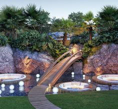 a water slide in the middle of a garden with palm trees and lights around it