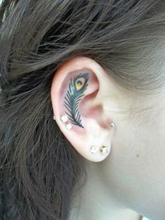 an ear with a peacock tattoo on it