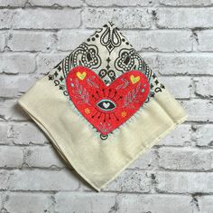 a red heart with an evil eye on it is hanging from a white brick wall