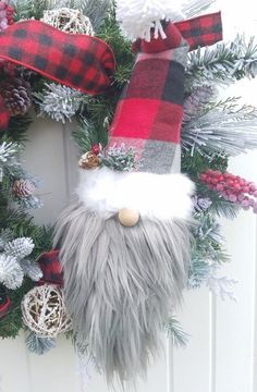 a christmas wreath with a gnome's nose and plaid scarf hanging on the front door