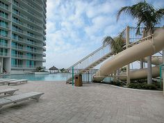 an empty swimming pool with water slides and lounge chairs in the foreground on a sunny day