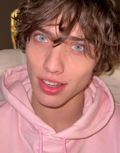 a close up of a person wearing a pink hoodie and looking at the camera