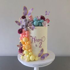 a white cake decorated with butterflies and balloons