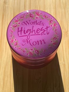 a pink container with the words world's highest mom on it sitting on a wooden surface