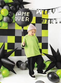 a little boy standing in front of some balloons