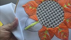 someone is stitching an orange flower on a piece of fabric