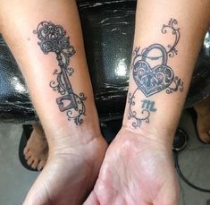 two people holding hands with tattoos on their arms and one has a key in the shape of a heart