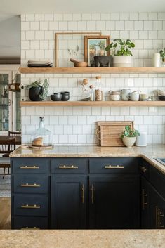 a kitchen with black cabinets and white subway backsplashes, gold trimmings