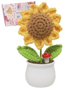 a crocheted sunflower sitting in a white vase with a mushroom on it