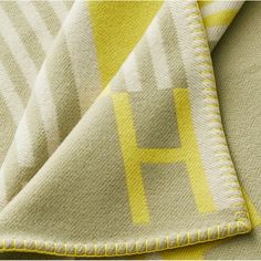 a yellow and white blanket with the letter h on it's side, folded in half