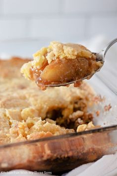 a spoonful of food is being lifted from a casserole dish with crumbs