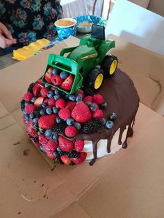 a cake decorated with strawberries, raspberries and blueberries on top of a cardboard box