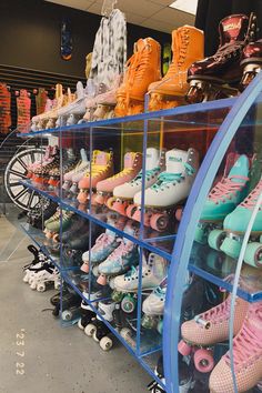 many pairs of roller skates are on display in a store with blue shelves and wheels