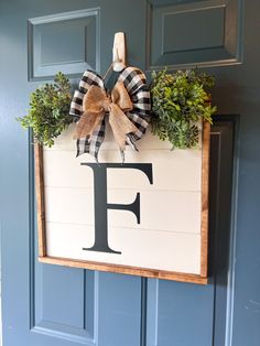 a wooden sign with a bow hanging on it's front door that says f