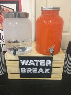 there is a water break sign next to two jars with lids on it and some cups in front of them