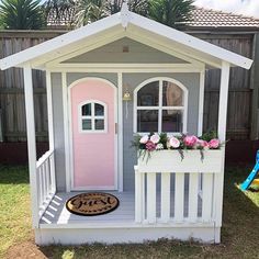 a small white and pink house with flowers in the window