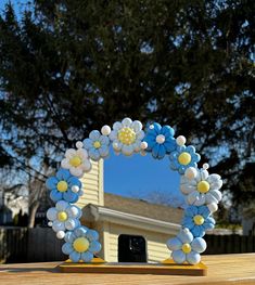 a blue and white wreath with flowers on it sitting on a table in front of a house