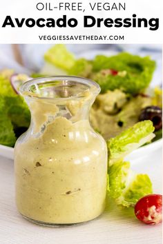 an image of avocado dressing in a small glass bottle with lettuce and tomatoes on the side