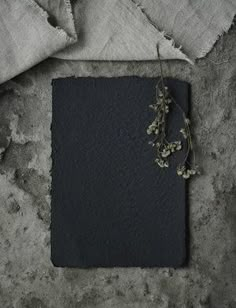 a piece of black paper sitting on top of a table next to a flower arrangement