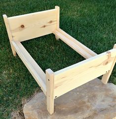 a wooden bed frame sitting on top of a stone slab in the middle of grass