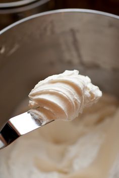 a spoon full of whipped cream in a metal bowl