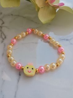 Perfect for Easter or just because! This pale yellow and pink pearl bracelet features the sweetest little chick face. It's sure to bring a smile to your face! These are handmade at the time of order and are made using high-quality stretchy cord and beads. However, they are delicate, and I recommend you do not wear while sleeping, swimming, bathing, or working out.   One size fits most. Standard bracelet size is 7 inches. If you need a custom size, please message me. Please measure your wrist bef Cute Handmade Pearl Bracelet Gift, Cute Gold Beaded Stretch Bracelet, Cute Beaded Pearl Bracelet As A Gift, Cute Beaded Pearl Bracelet As Gift, Cute Beaded Pearl Bracelet Gift, Cute Adjustable Pearl Bracelet Gift, Pink Novelty Stretch Bracelet For Birthday, Novelty Pink Stretch Bracelet For Birthday, Sweet Adjustable Stretch Bracelet For Gift