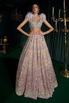 Step into refined elegance with this enchanting lehenga set, inspired by the undertones of the dawn sky, where pink, blue, and glimmering stars come to life. Crafted from delicate net, it features radiating sequins in gold, blue, and pink, beautifully accentuated by resham work. The intricate detailing mirrors the stars, ensuring that every movement radiates brilliance. The blouse showcases a modern reverie with feather detailing, perfectly complemented by a net dupatta adorned with a graceful b Brown Lehenga, Sequins Lehenga, Dawn Sky, Resham Work, The Undertones, Net Dupatta, Purple Fabric, The Dawn, Blue And Pink